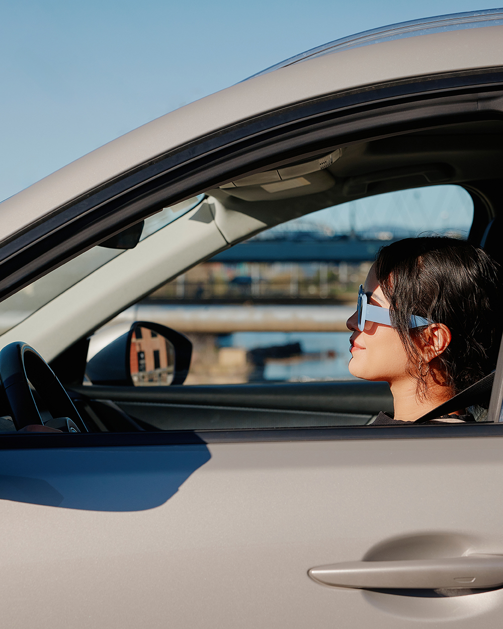 Woman driving an electric vehicle with a scenic city view and tower in the background