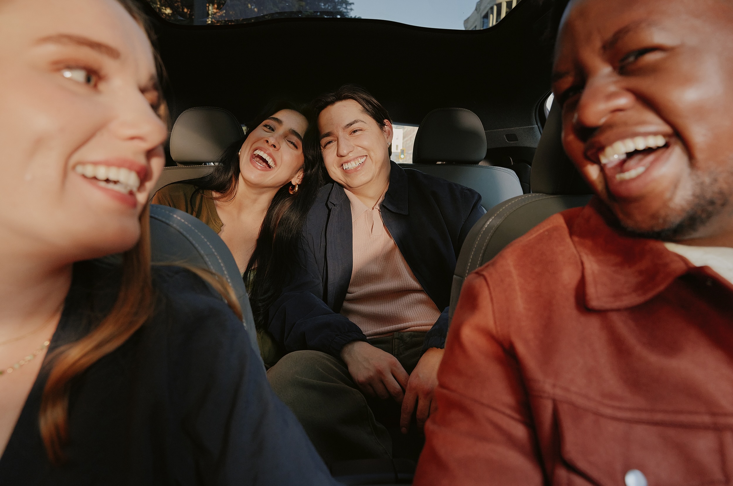 Four people smiling inside of a car.