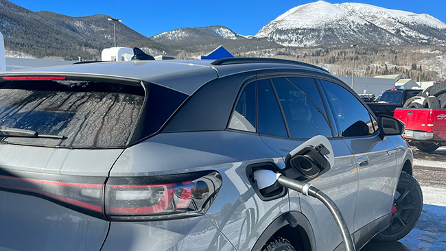A picture of Greg's VW ID.4 Pro S being charged in a parking lot with other cars and mountains in the background.