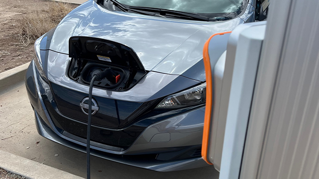 A picture of Laura's silver Nissan Leaf being charged in a parking lot.