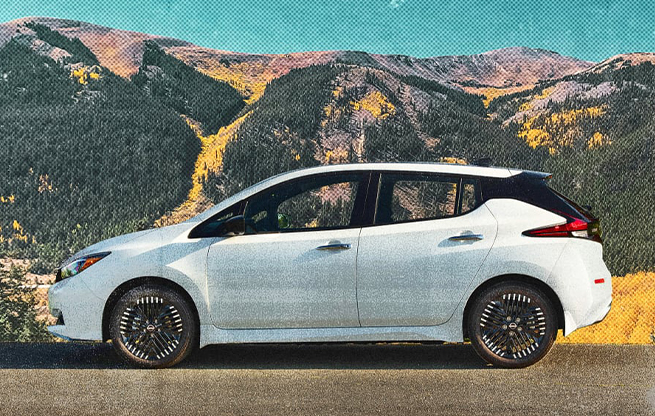 A white hatchback parked in front of a mountainous landscape.