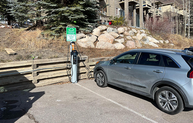 Gray car charging at an electric vehicle charging station.