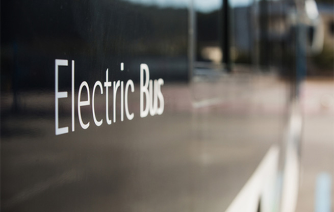 A close up photo of the side of a vehicle, showing the words: Electric Bus