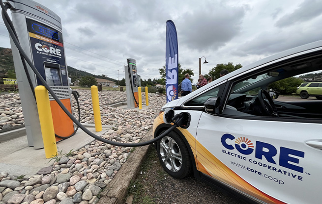 An electric vehicle charging in a stone-covered parking lot