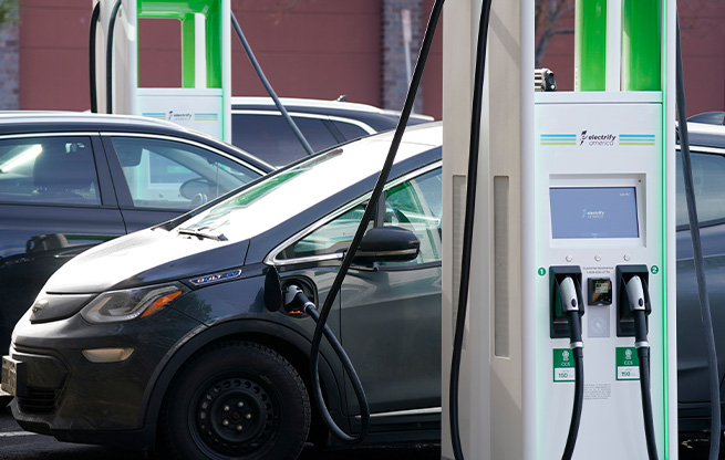 An electric vehicle charging at a charging station that closely resembles a traditional gas station