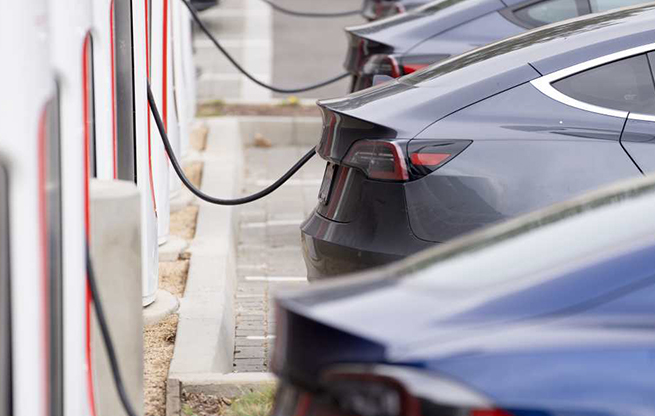 A row of Teslas charging in a parking lot