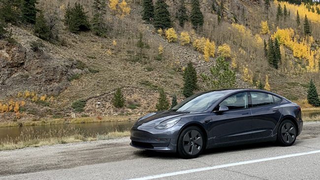 An image of Elizabet's navy Tesla Model 3 on the shoulder of the Million Dollar Highway.