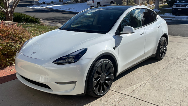 A picture of Jamie's white Tesla Model Y from the front left, parked.