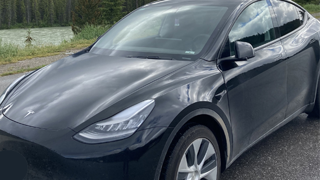 A close picture of Kart's black Tesla Model Y from the front left, parked.