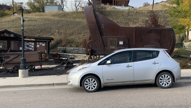 An image of Matt's silver Nissan Leaf from the driver's side, parked in front of a monument.