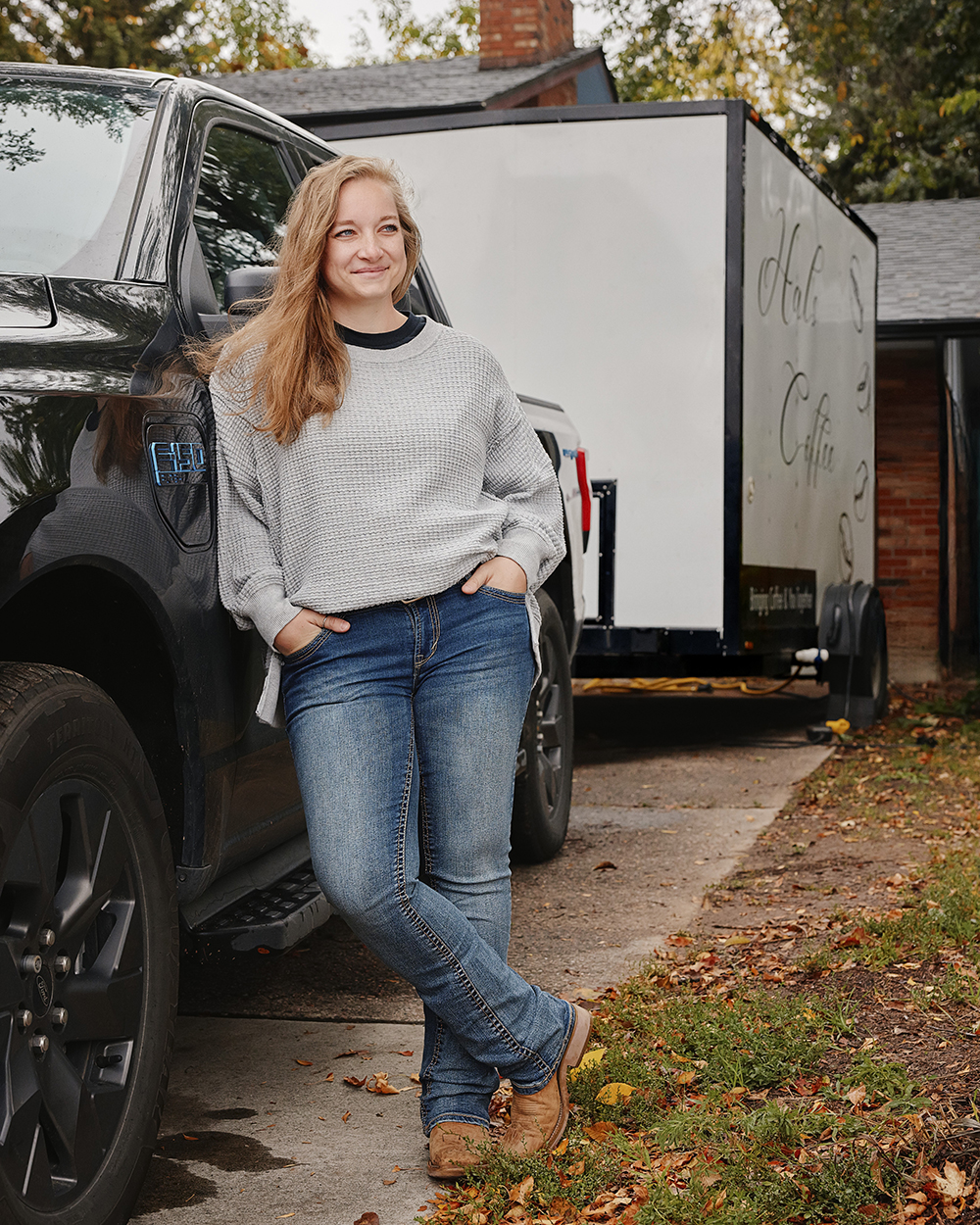 Woman standing against EV pickup trick