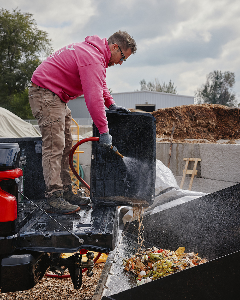 Man spraying out bin with water