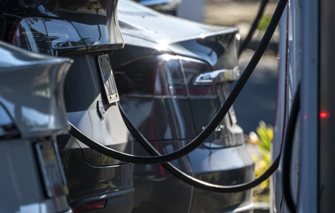 Rear view of three cars charging in a row
