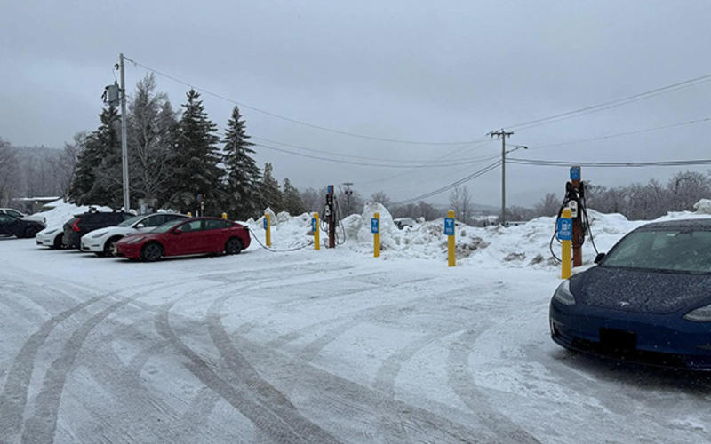 A bank of EV chargers in a snow-covered parking lot