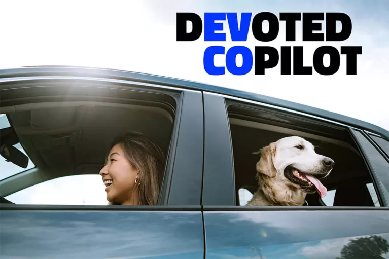 EV CO: Devoted Copilot. A woman and a dog in an electric vehicle.