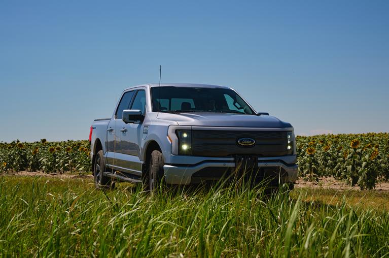 A Ford F-150 Lightning parked in a field of tall grass.